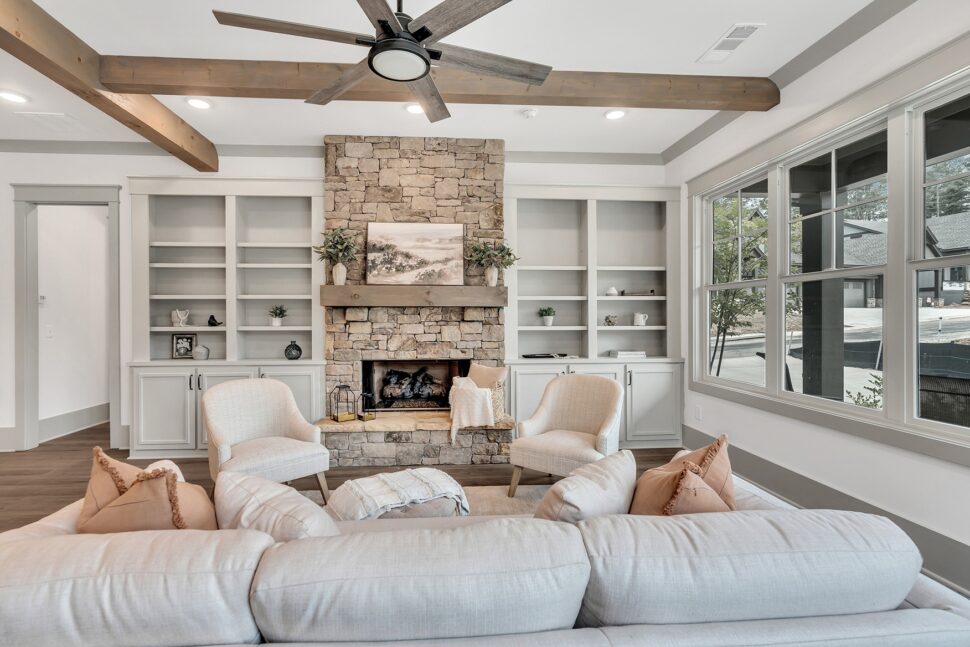 Cozy living area with stone fireplace, built-in shelves, and large windows bringing in natural light.