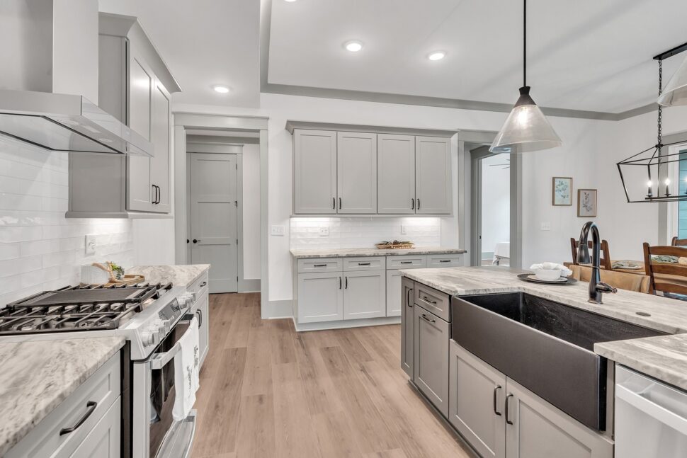 Modern kitchen with gray shaker cabinets, large farmhouse sink, and marble-look countertops.
