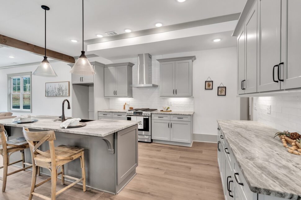 Bright kitchen with pendant lights, stainless steel appliances, and large center island with seating.
