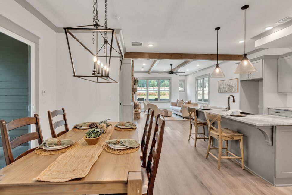 Open dining area with rustic wood table and clear sightline to living room and stone fireplace.