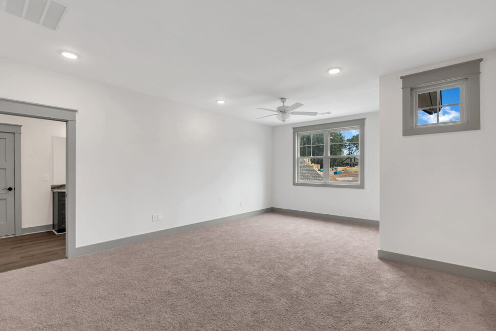Spacious carpeted bonus room or guest suite with ceiling fan, recessed lighting, and large window views.